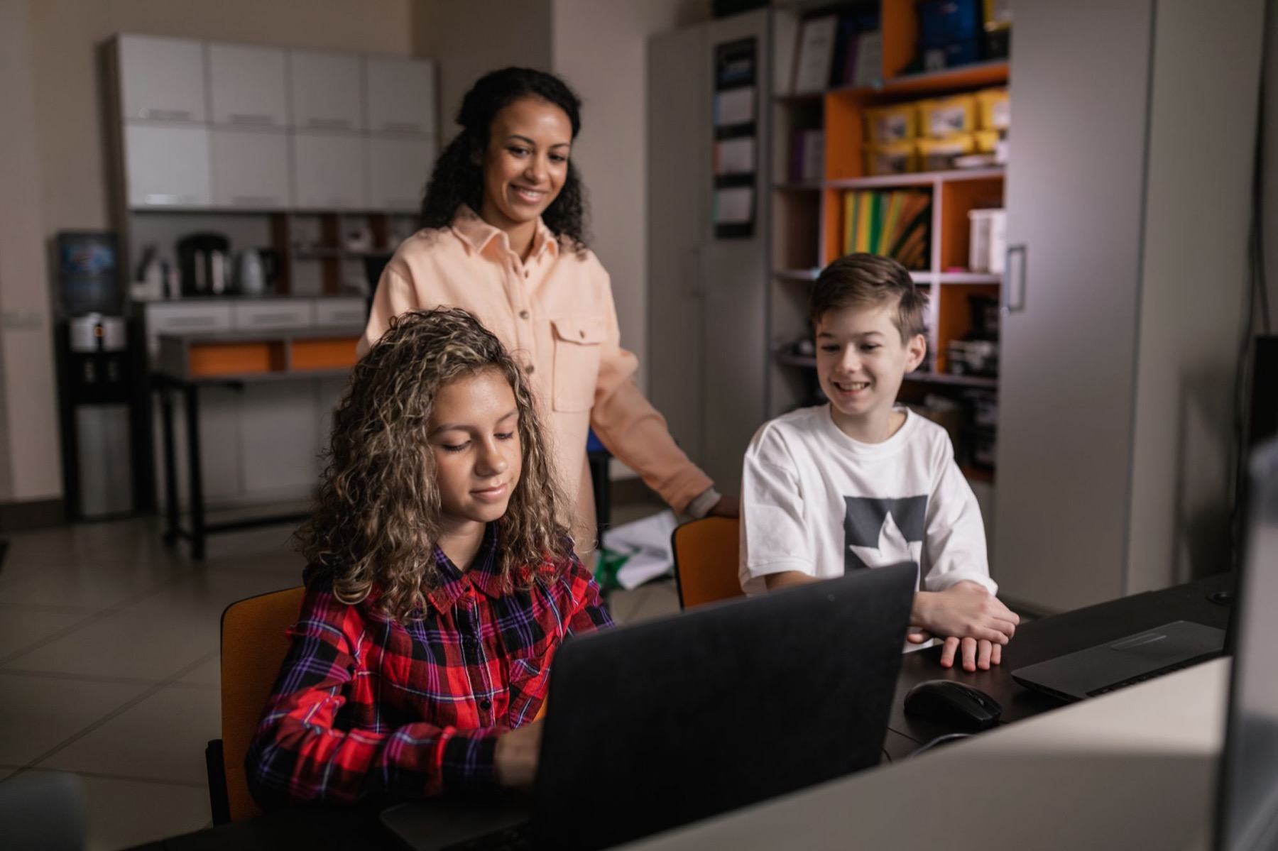 A teacher and two young learners exploring a computer together