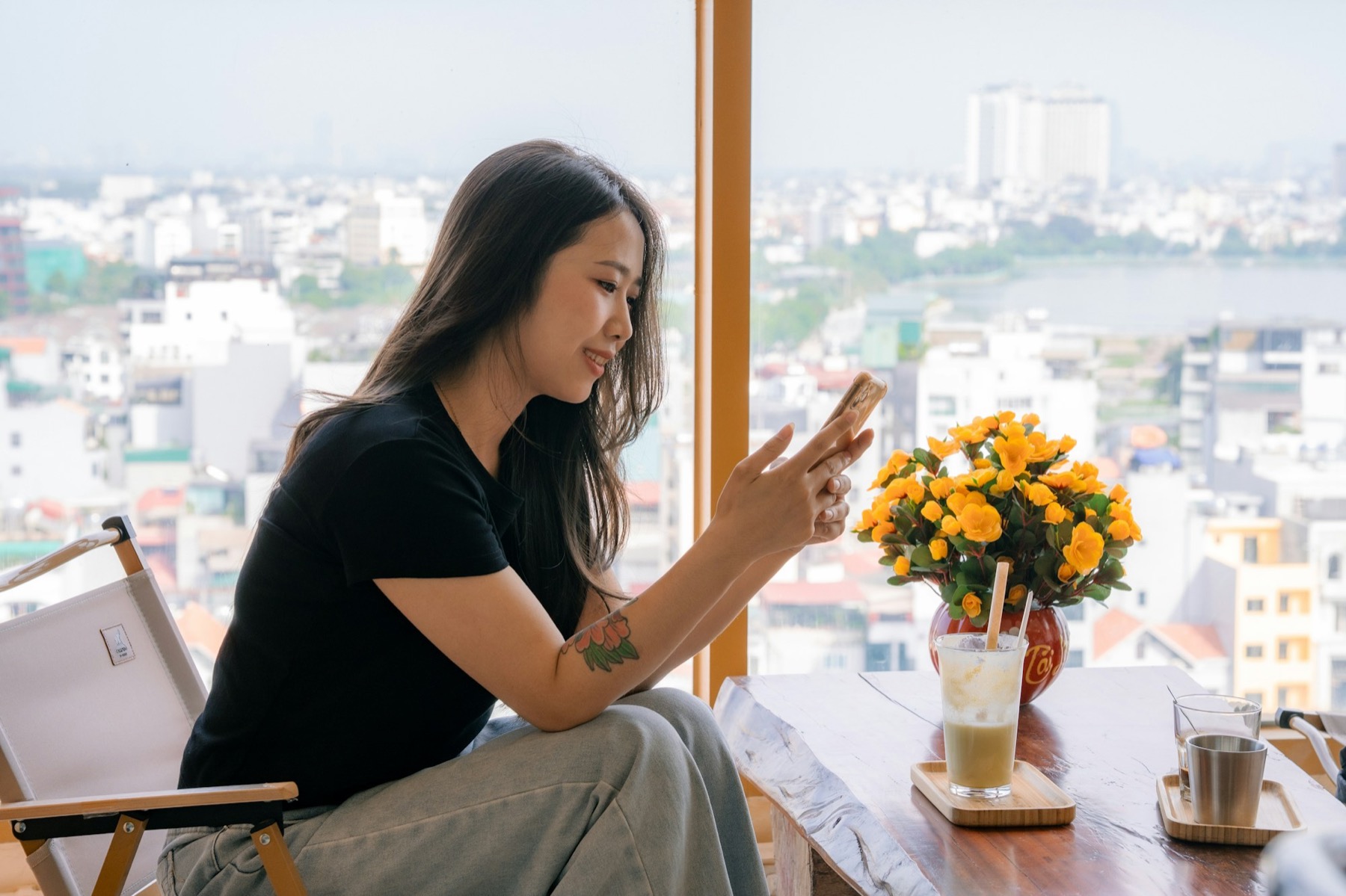 A young woman exploring something on her phone by a window